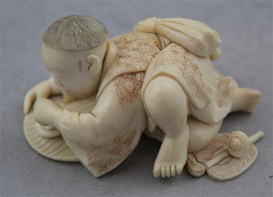 A Japanese carved ivory okimono of a child with a spinning top, 19th century, 17.6cm